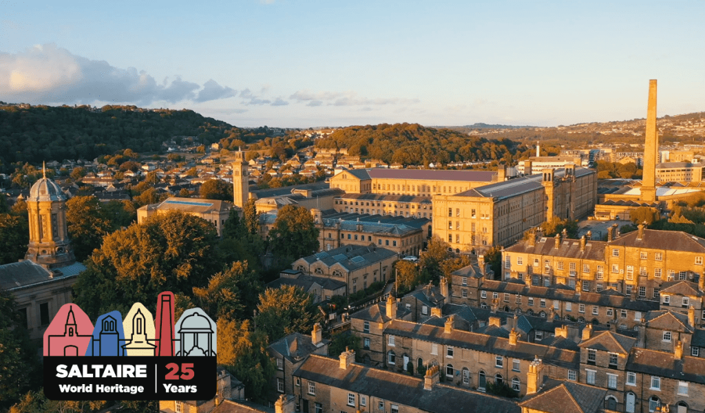 a view over the village of saltaire, with rows of brick houses surrounding a large mill