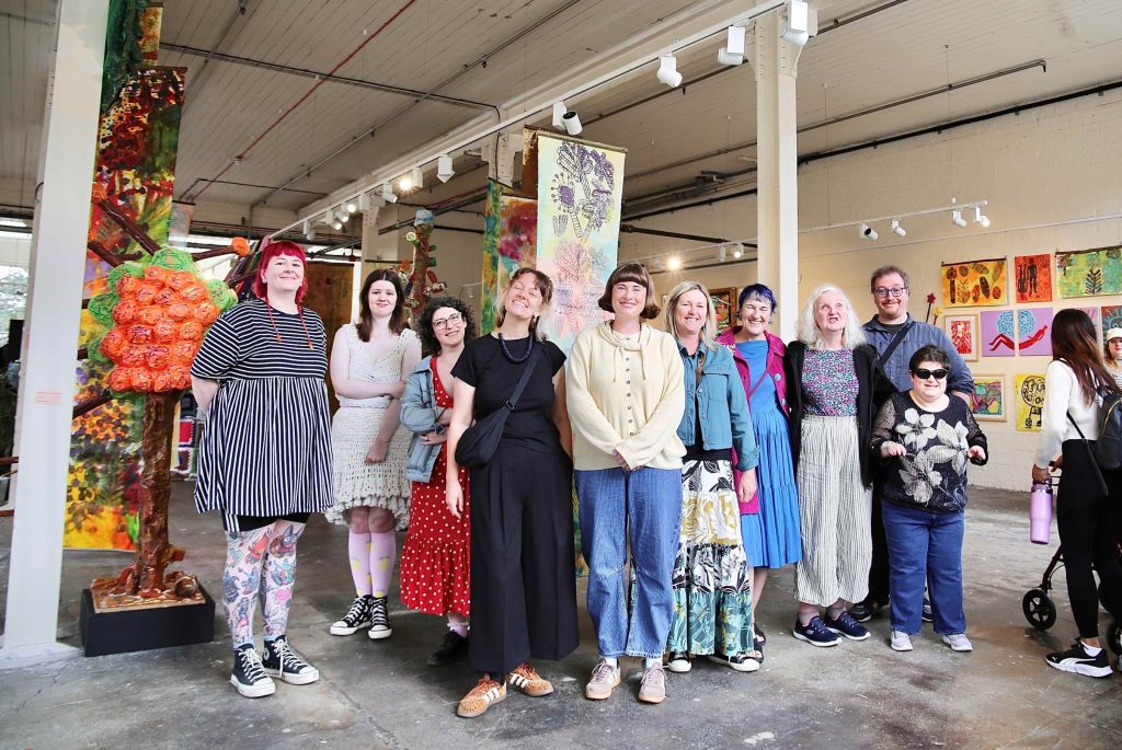 a group of people standing in an old mill industrial room with iron beams, all posing looking at the camera