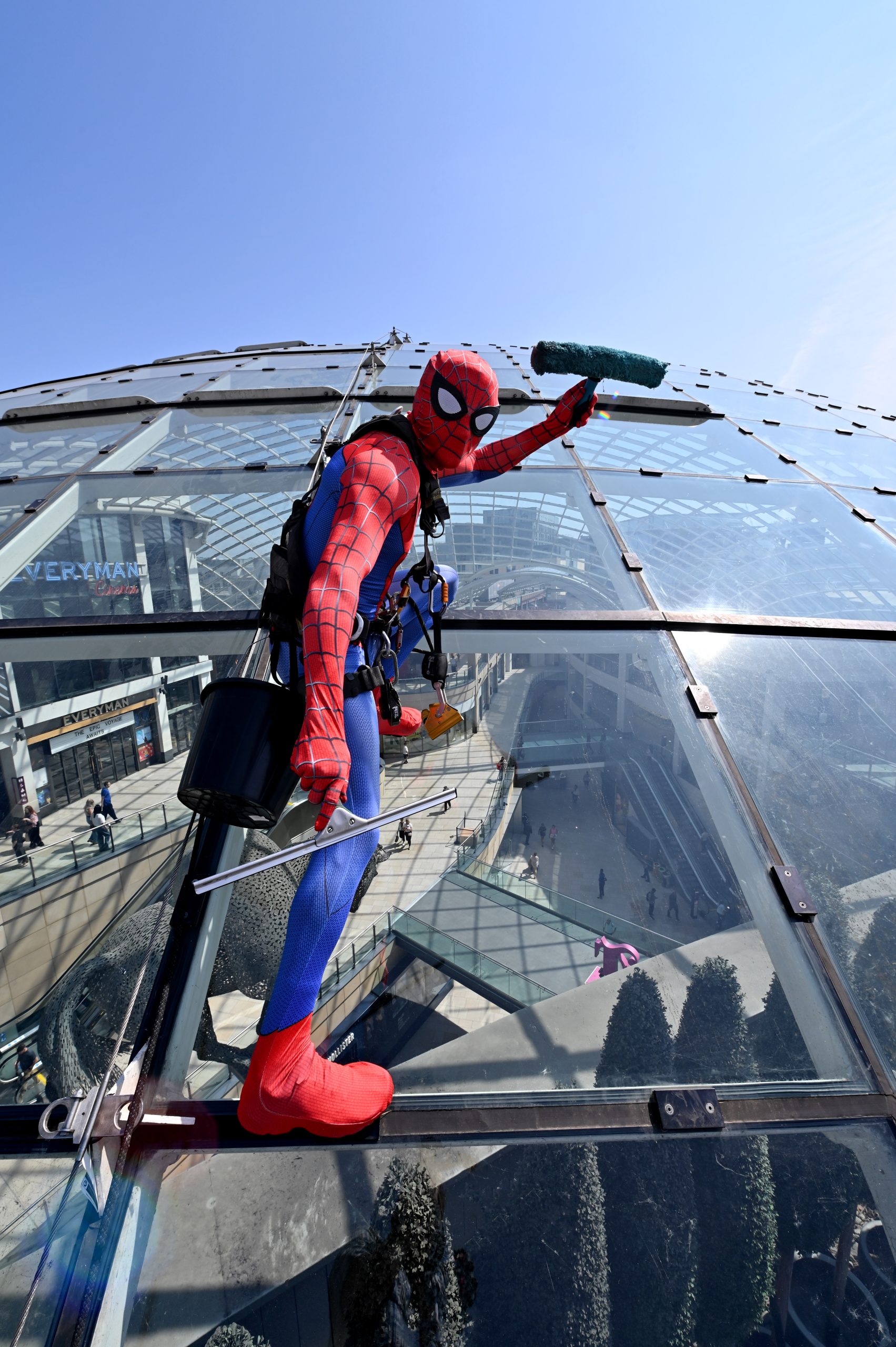 a person on the roof of a glass dome dressed in a spiderman costume