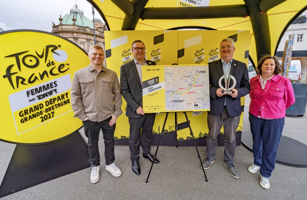 four people stood around a board showing a map with a yellow awning around them
