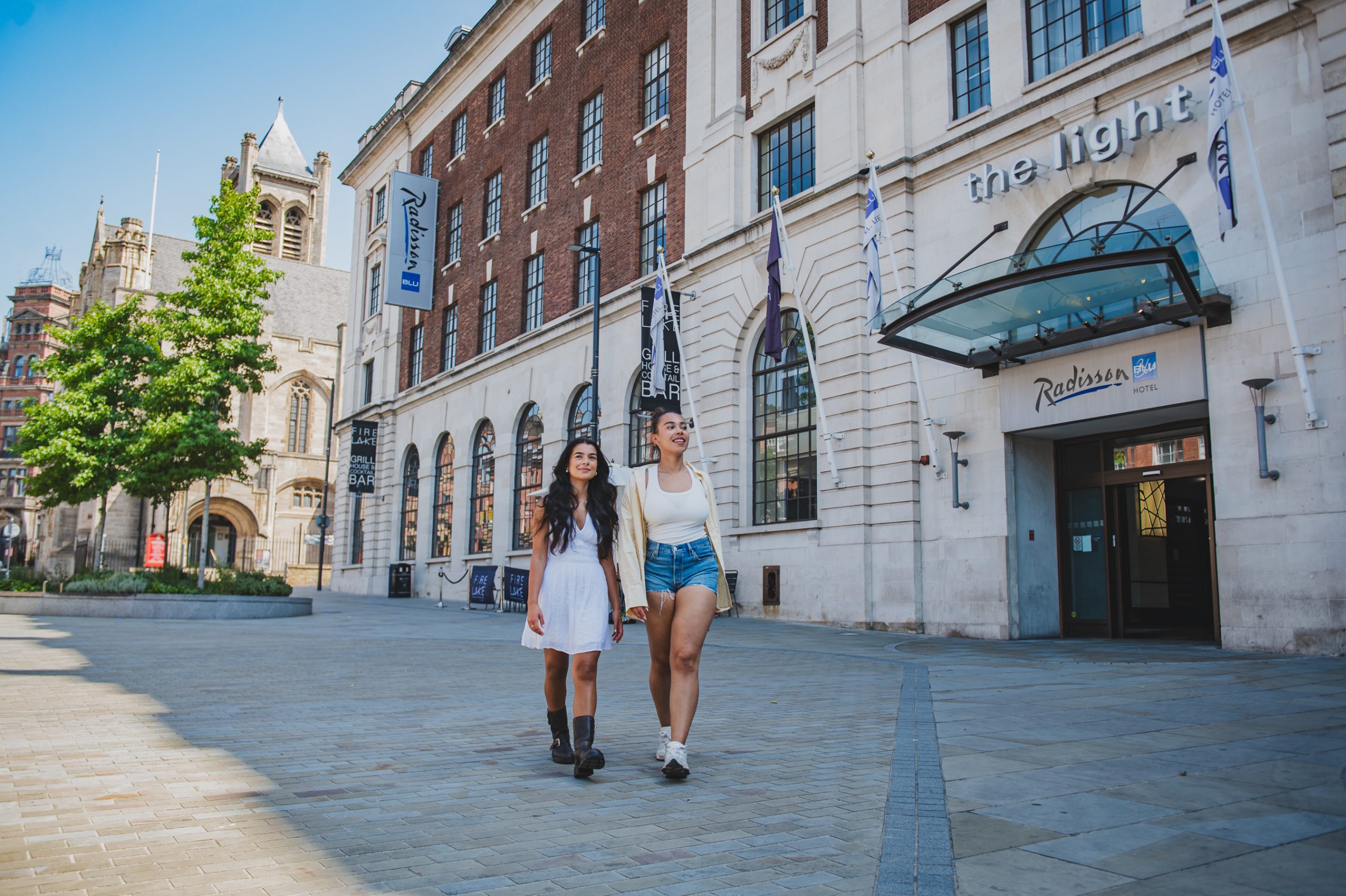 two people walking along the side of a large white and brown building