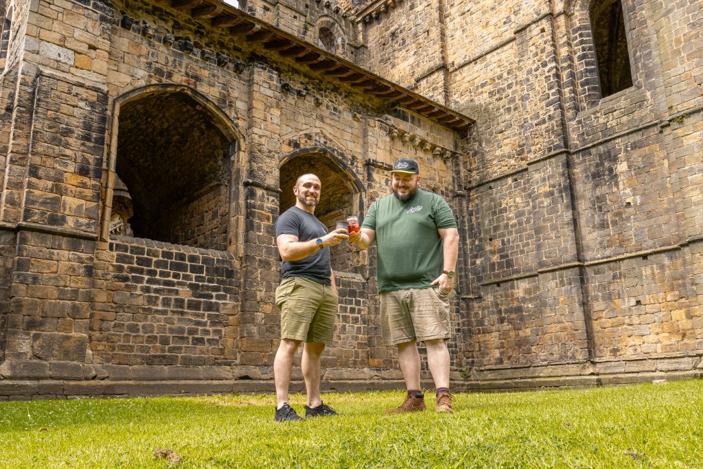 two men stood on grass in the ruins of an old abbey