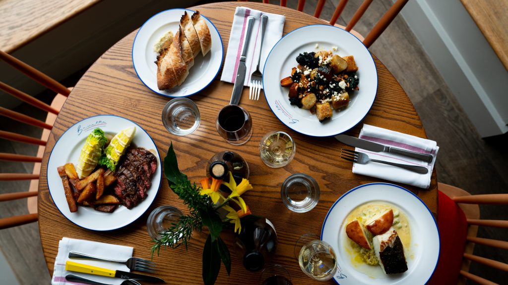 View of a selection of dishes and drinks on a table shot from above at Bavette Bistro