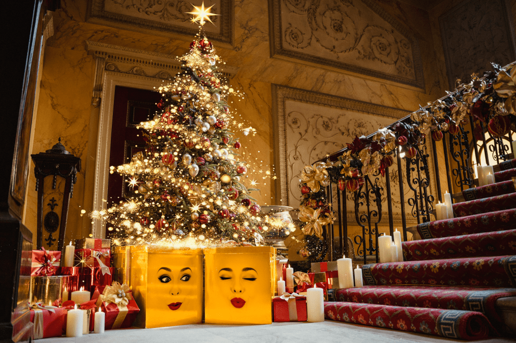 a christmas tree with several presents underneath it at the bottom of an ornate staircase, with two presents having faces
