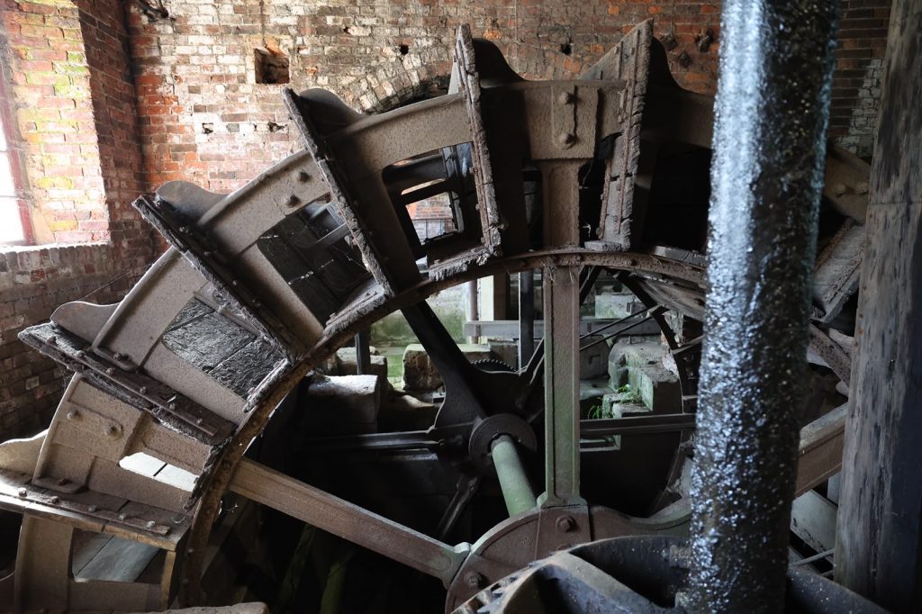 the interior of an old brick mill with a large metal water wheel