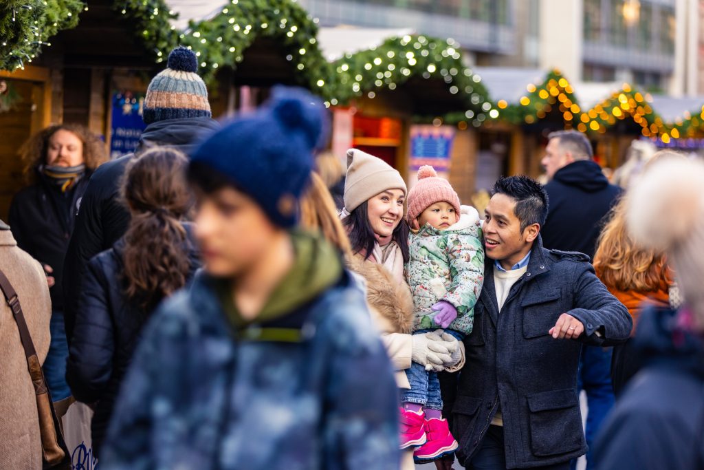 Family enjoying Leeds Christmas market in woolly hats on a cool crisp day