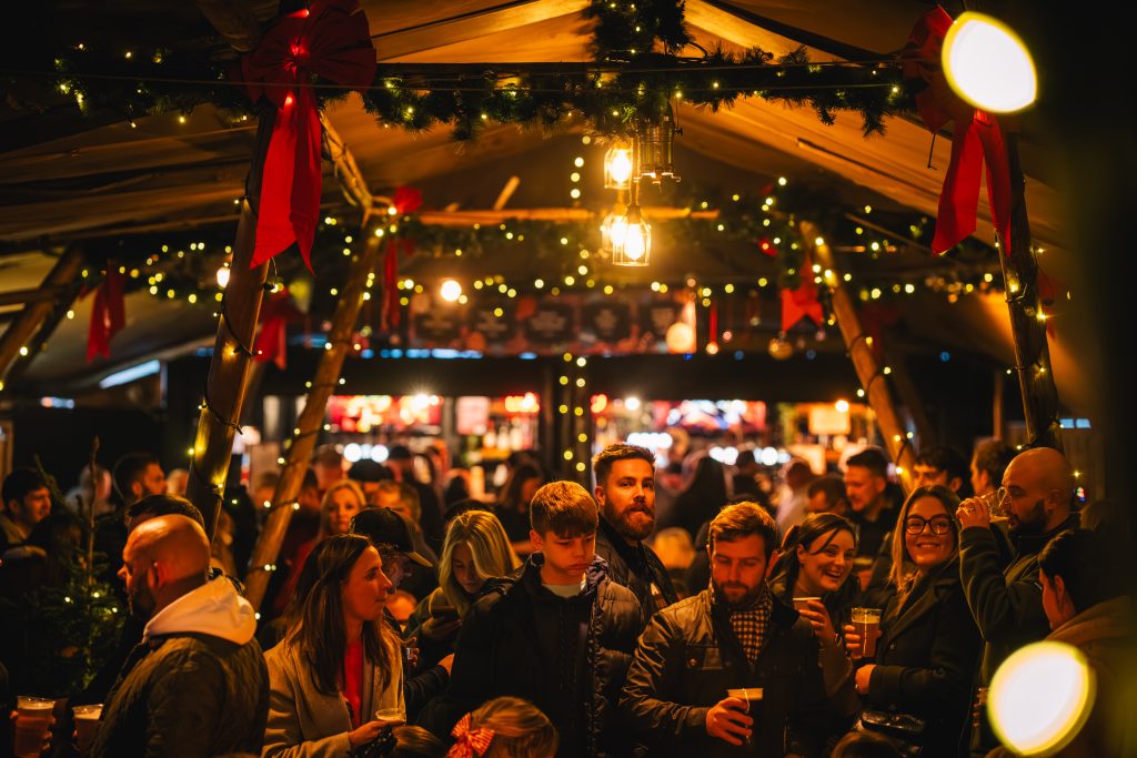 Crowds of people in glowing gold light enjoy Thor's Tipi and Leeds Christmas Markets