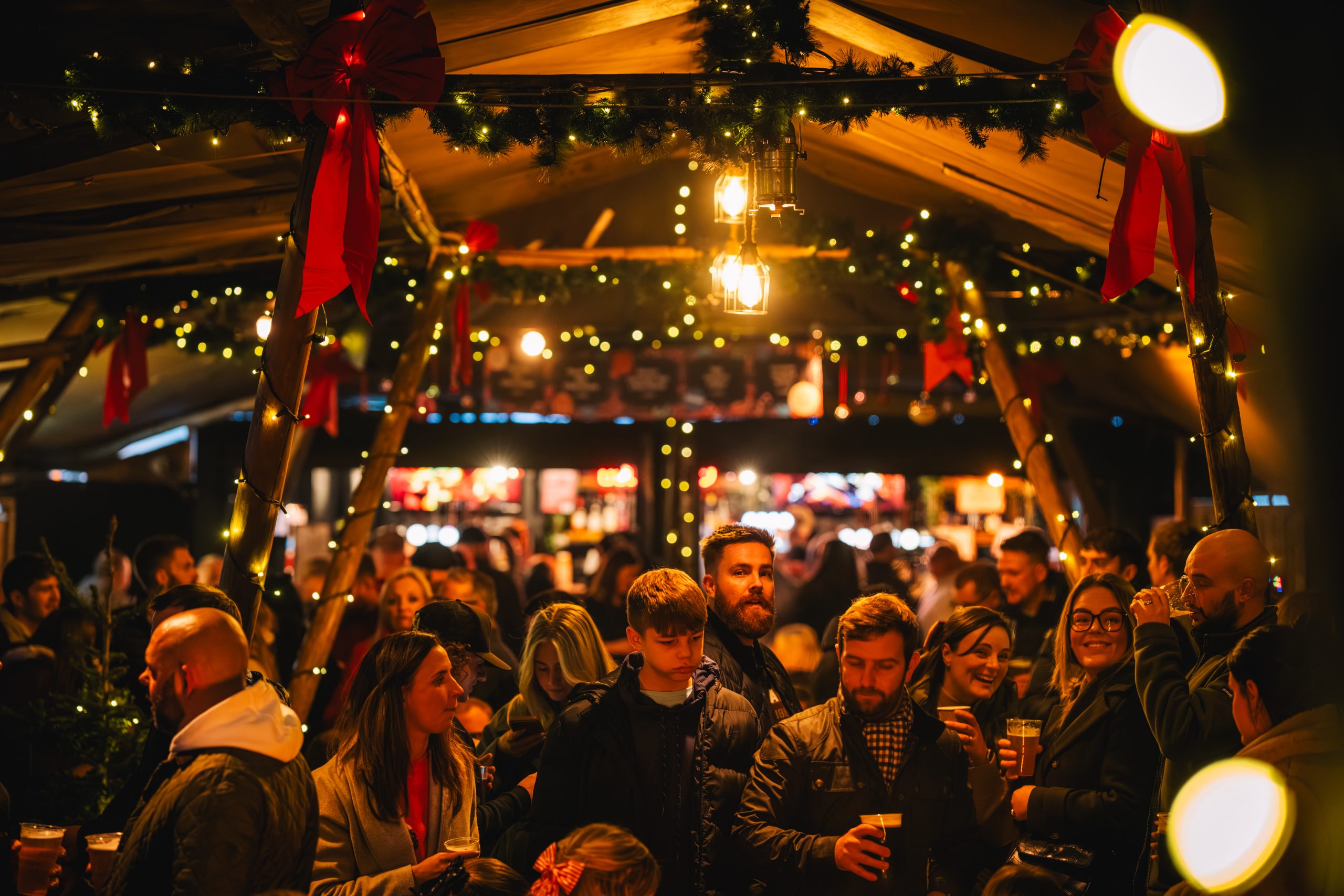 Crowds of people in glowing gold light enjoy Thor's Tipi and Leeds Christmas Markets