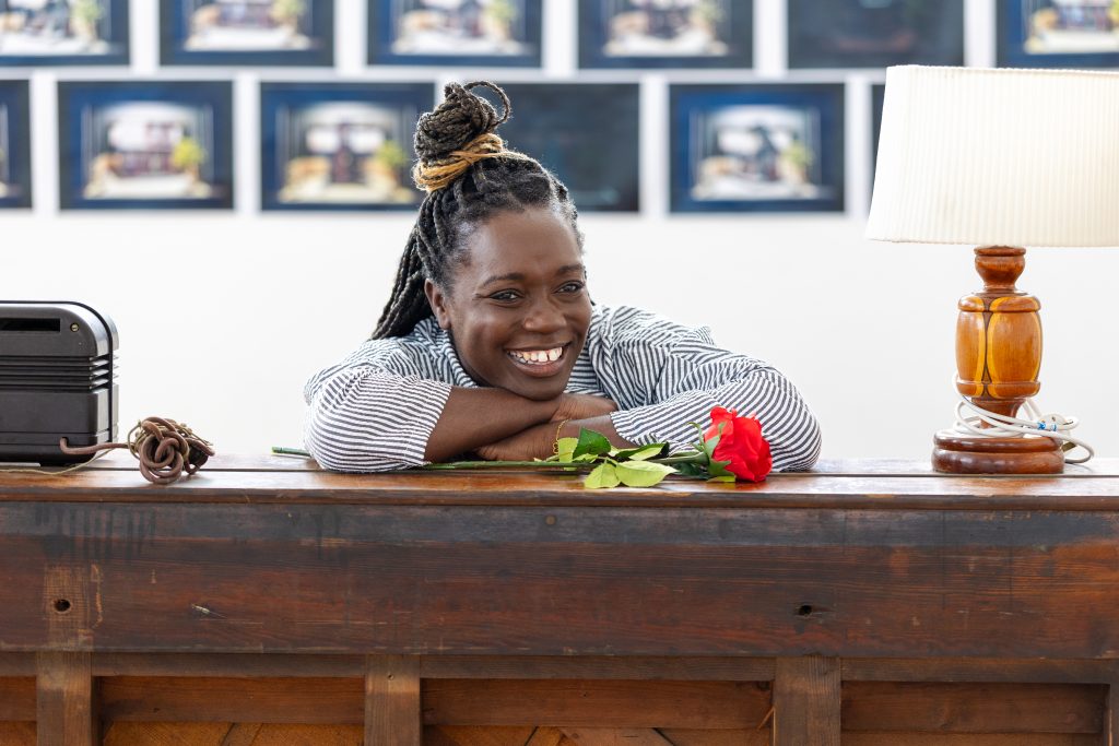 a woman leaning on a wooden piano with a rose on top