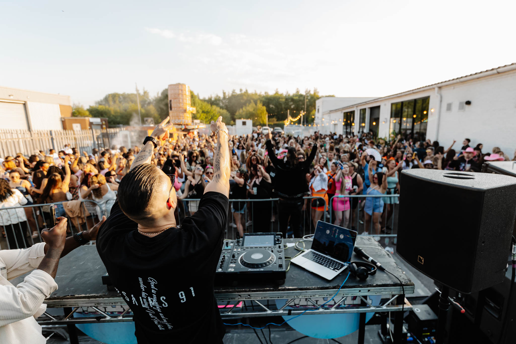 a crowd of people outside watching a dj at sundown