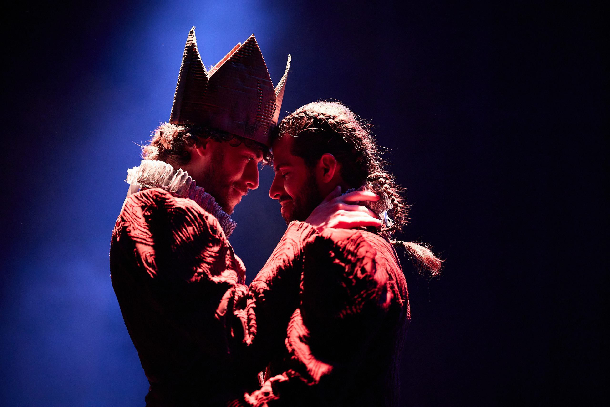 two people standing under a spotlight with their foreheads touching