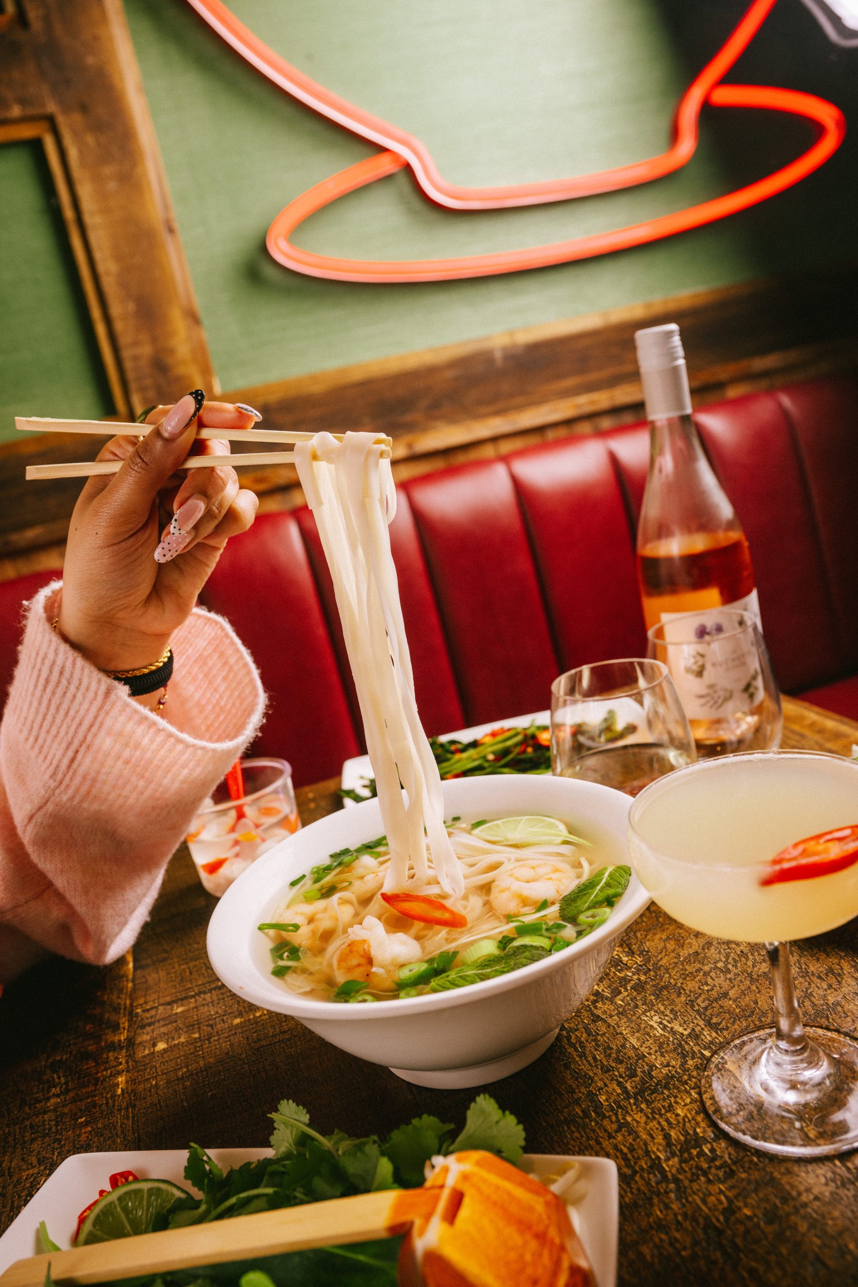 a table setting with something pulling noodles out of a bowl with chopsticks
