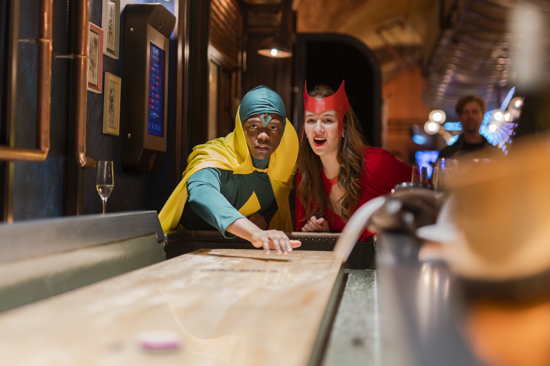 two people at the end of a shuffleboard dressed in superhero costumes