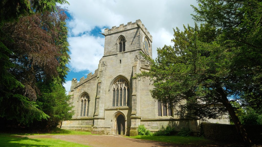 a large stone church surrounded by trees on a cloudy day