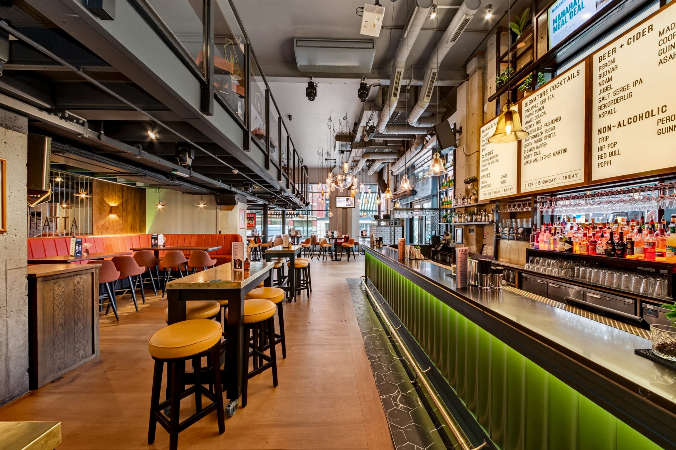 the interior of a bar with a long bar on the right and tables and chairs to the left