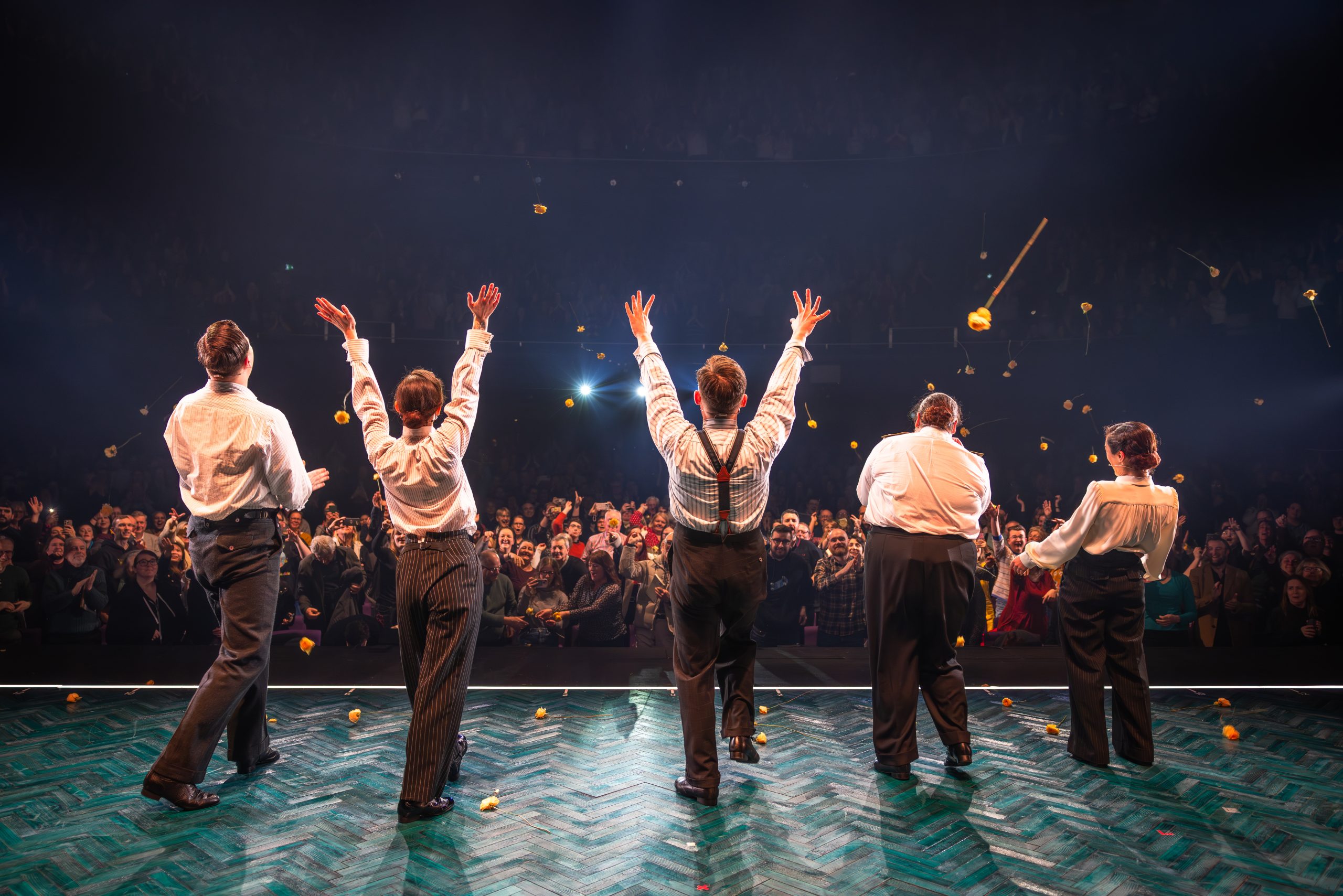 several people on stage performing to a crowd at a theatre